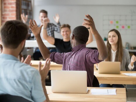 Feiernde Klassenzimmerszene Menschen in einem Klassenzimmer feiern und applaudieren.